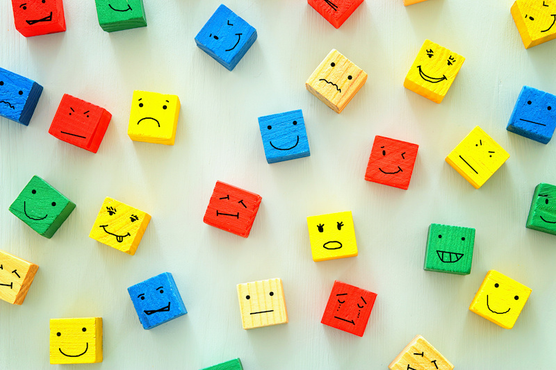 concept of Different emotions drawn on colorfull cubes, wooden background.