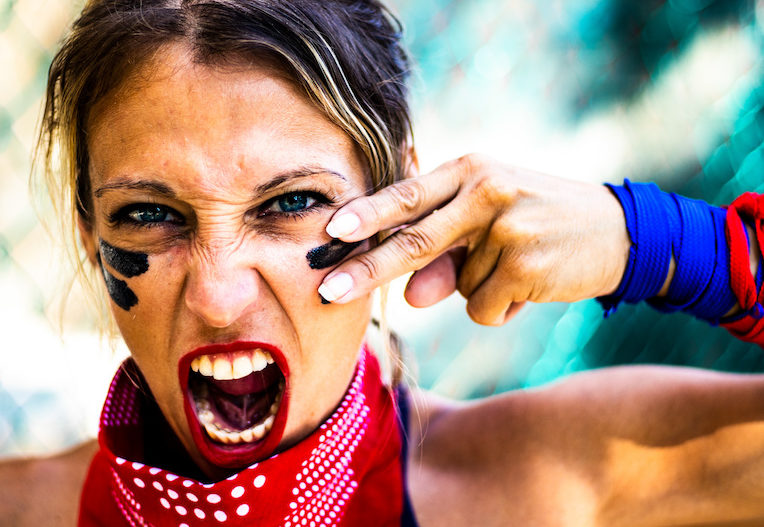 Young and strong woman with blue eyes applying face paint